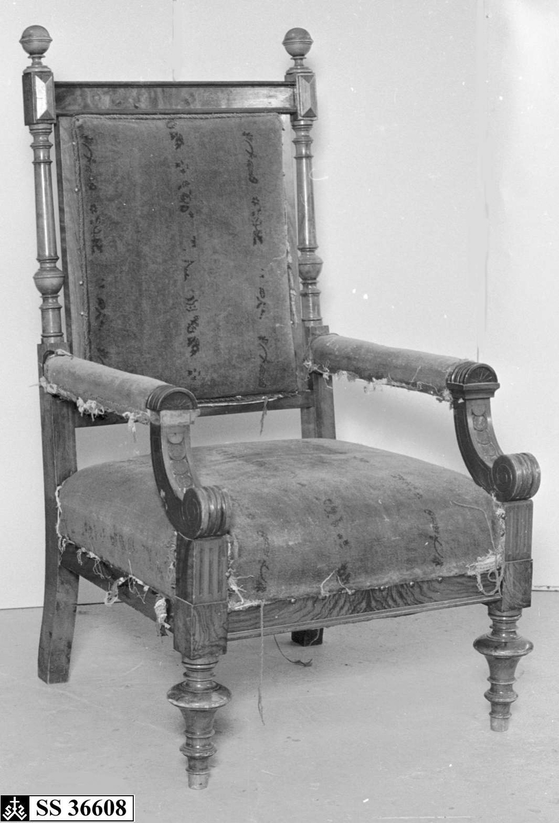 Stolen er av palisand og bjørk med dreide bein og dreide søyler i stolryggen. Sete og rygg er stoppet, armlenene delvis, med rødt tekstil. Stolen gåt stilhistorisk under nyrenessanse.