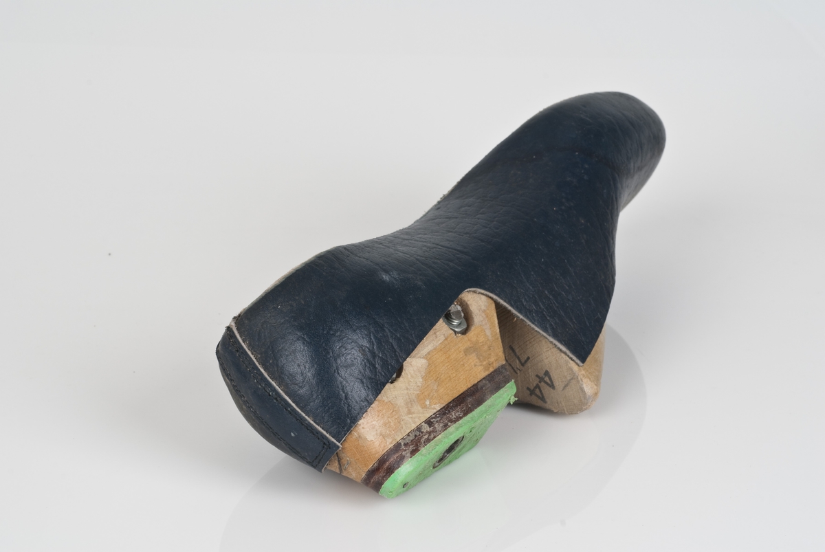 En trelest med overlæret til støvel (fabrikkstøvel).
Høyrefot i skostørrelse 44, med 7,5 cm i vidde.
Skinntrekket er i blåfarge.
Lestekam av plast i grønnfarge, og skinn.

