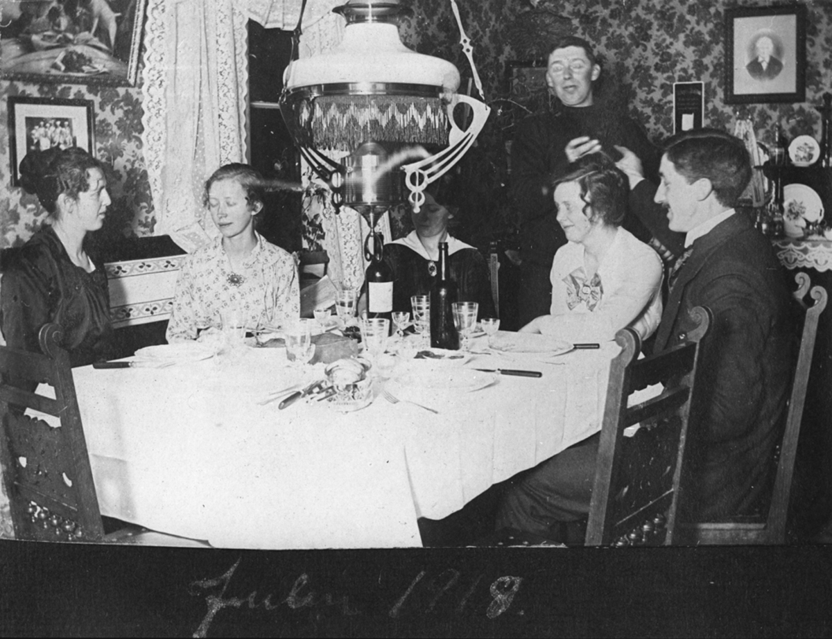 Julen 1918. Kvinner og menn samlet rundt oppdekket middagsbord.