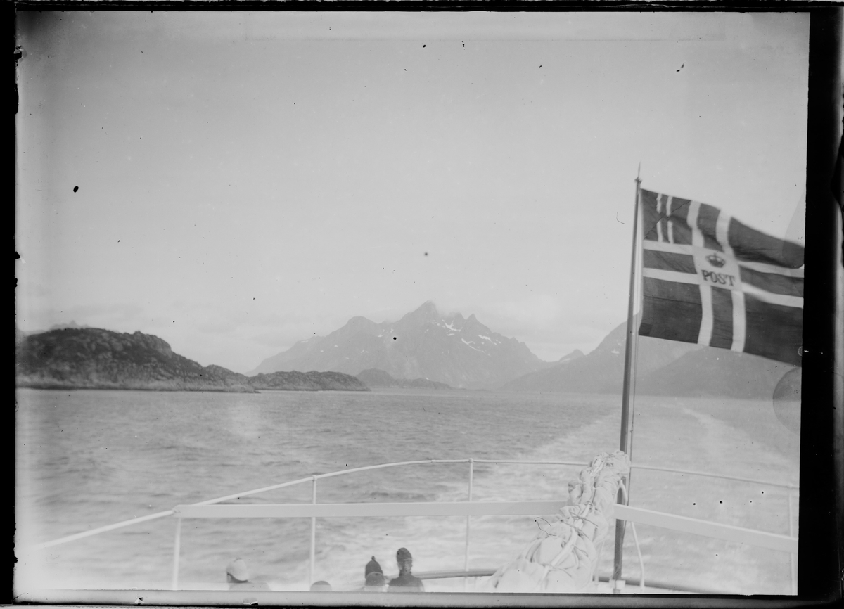 Fjord og fjell sett fra postbåten. Postflagg til høyre.