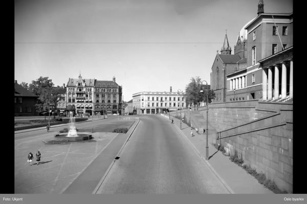 Henrik Ibsens gate (nåværende Hammersborggata) og Arne Garborgs plass mot Akersgata med Deichmanske bibliotek og Trefoldighetskirken til høyre. Fotografert i forbindelse med planlegging av tunnelbane.