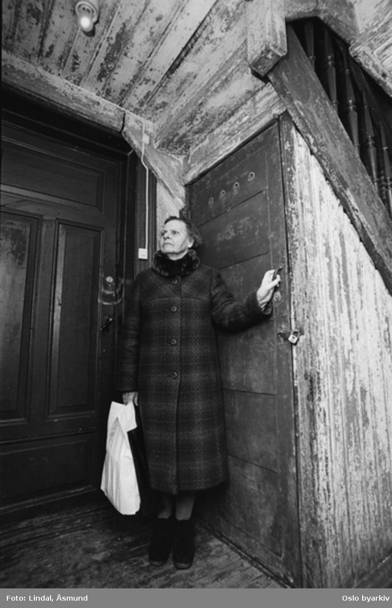 Eldre dame foran døra ned til kjelleren. Bildet er publisert på s. 30 i boken Oslo-bilder. Fotografiet er fra prosjektet og boka ''Oslo-bilder. En fotografisk dokumentasjon av bo og leveforhold i 1981 - 82''. Kontakt Samfoto ved ev. bestilling av kopier.