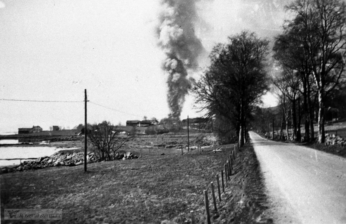 Molde april 1940, Fannestrandsvegen vestover mot Moldegård. Vi ser ei røyksøyle stige opp fra sentrum.