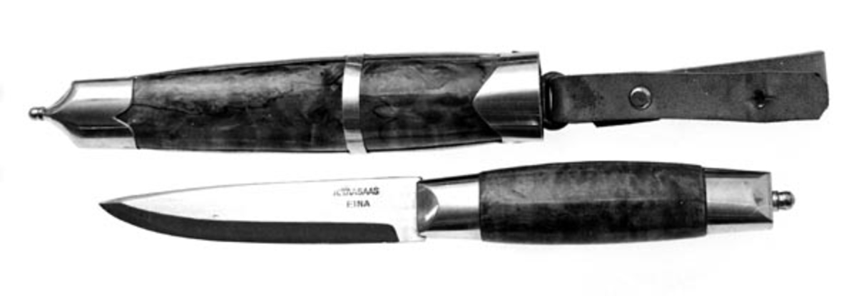 Knivbladet er smidd av Aksel Taasaas og kniven er laget av han. Skaftet og slira er av valbjørk og brunbeiset. Slike valbjørkkniver var den ene av de to typene Totenkniver som ble produsert i stor målestokk fra midten av forrige århundre. Den andre hadde horn i skaft og slire. 