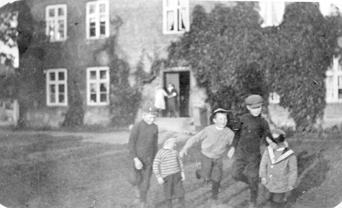 Barn i lek utenfor hovedbygningen på Mellom-Kise, Nes, Hedmark. Kort sendt jula 1915 fra Hans og Even til Anne Dystvold gift Olstad. Hun har vært husjomfu her.