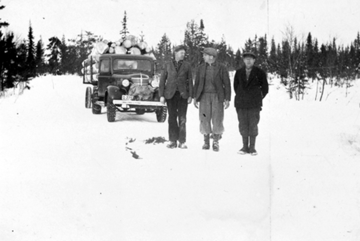 Tre skogsarbeider foran lastebil med tømmer. Fra venstre er Einar Jevanord, Alf Nordengen, Magne Solheim. Lastebilen er Chevrolet 1938 modell med norskbygd førerhus, trolig treseters. Tilhørende Ludvig Ødegarden, Basarud, Furnes Almenning.