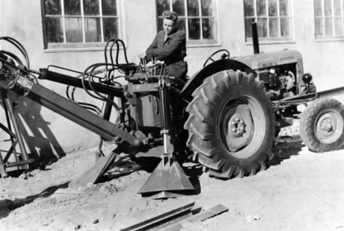 Traktor med gravemaskin produsert av Hymas A/S, Brumunddal. Ukjent mann på traktor.