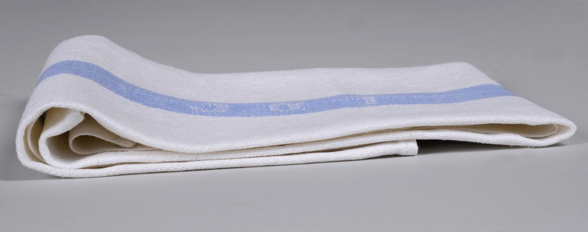 Rektangulær kopphånduk i hvitt og blått, fiskebensvev. Innvevd S & T i den blå stripa. (Salvesen og Thams). Duken har en hempe påsydd ene kortsida, og har lagt opp en kant på ca 1 cm.