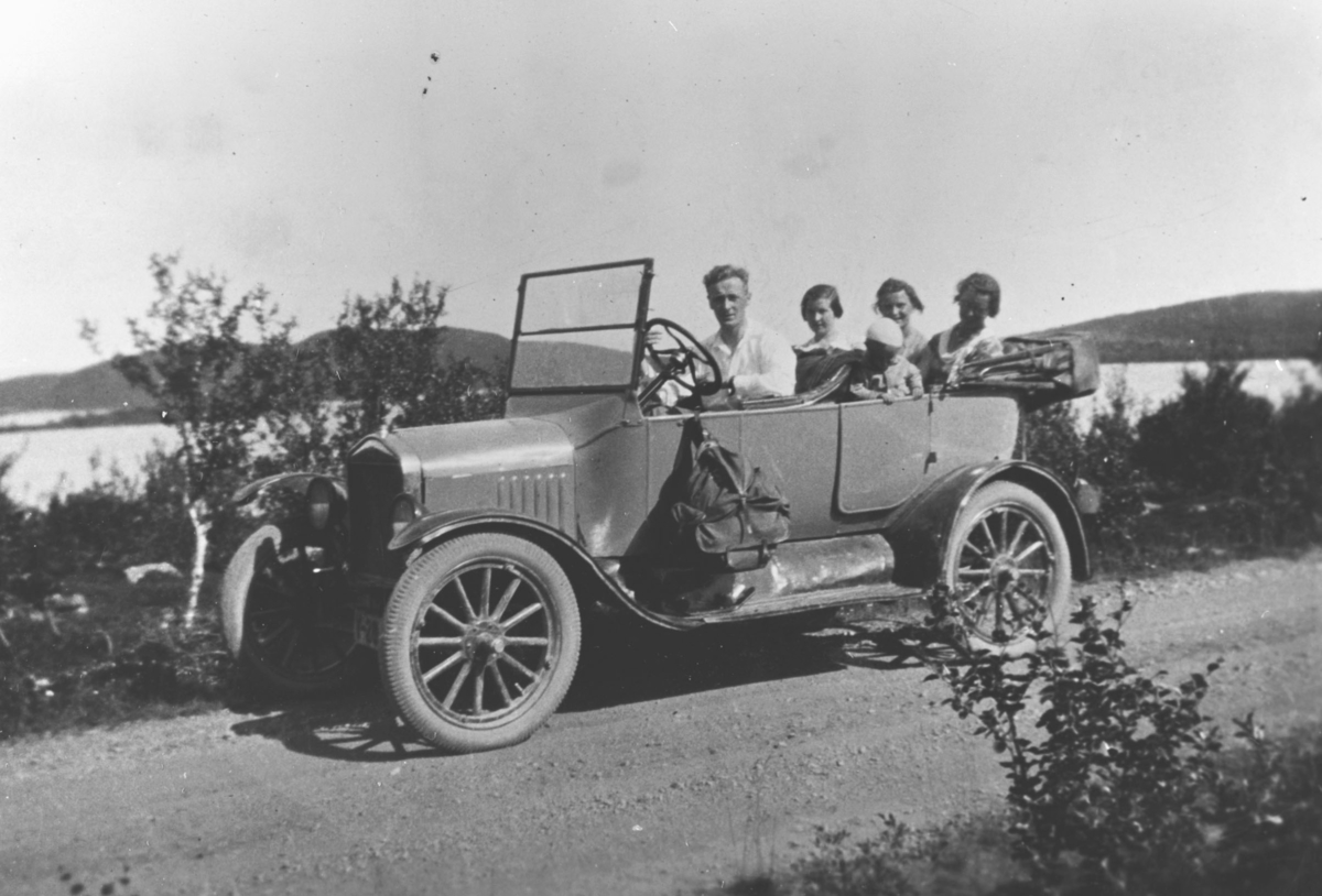 Familie på tur med bil på grusvei i fjelllandskap. Bilen er en Ford modell T 1925.
