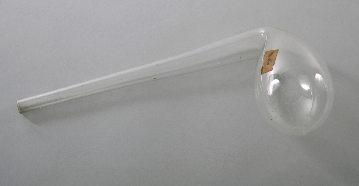 En dråpeformet kolbe av glass med et vinklet smalende rør som utløp. På utsiden av bøyen er det et utløp med propp av glass.