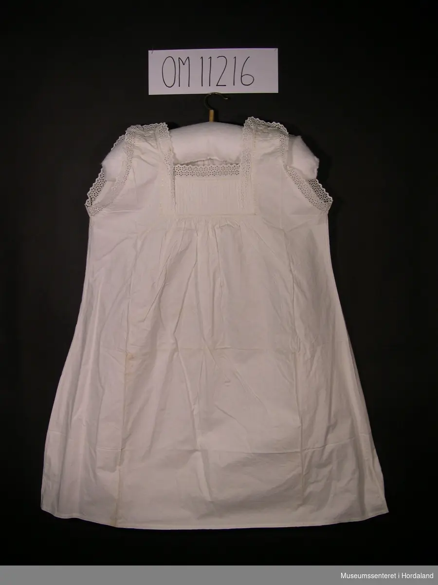 Form: ermelaus nattkjole med knapping på skuldrane og engelsk broderi på brystet og rundt ermer og hals
