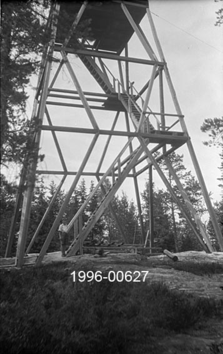 Tårnet på Garsjøberget skogbrannvaktstasjon sørøst for Disenå i Sør-Odal.  Anlegget lå 382 meter over havet.  Det første tårnet i dette området ble reist for Mads W. Stang i 1908, men dette tårnet er antakelig det som Ole A. Stang fikk bygd på ei noe annen tomt i 1922.  Det siste tårnet her ble for øvrig bygd i armert betong i 1939. 

Fotografiet viser den nedre delen av en bratt pyramidal stolpetårnkonstruksjon, avstivet av krysslagte stokkestag i tre nivåer og med ei utkikkshytte på toppen.  Fotografiet gir viser spesielt godt trappeløsningen opp mot luka i golvet på utkikkshytta i toppen av konstruksjonen. Tårnet er omgitt av en god del furutrær. 