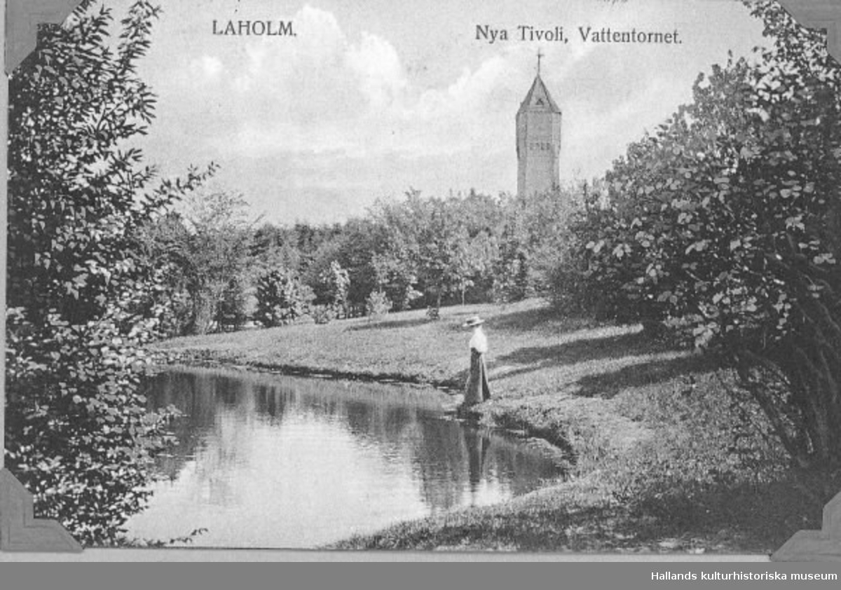 Vy över en damm i parken Nya Tivoli, Laholm. Vid dammen står en kvinna. I bakgrunden syns ett vattentorn.