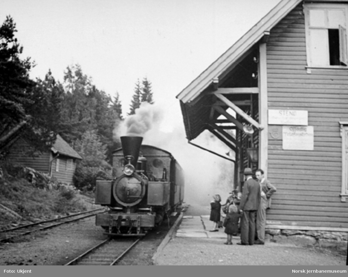 Nesttun-Osbanens tog med damplokomotivet "Os" ankommer Stend stasjon; reisende på plattformen