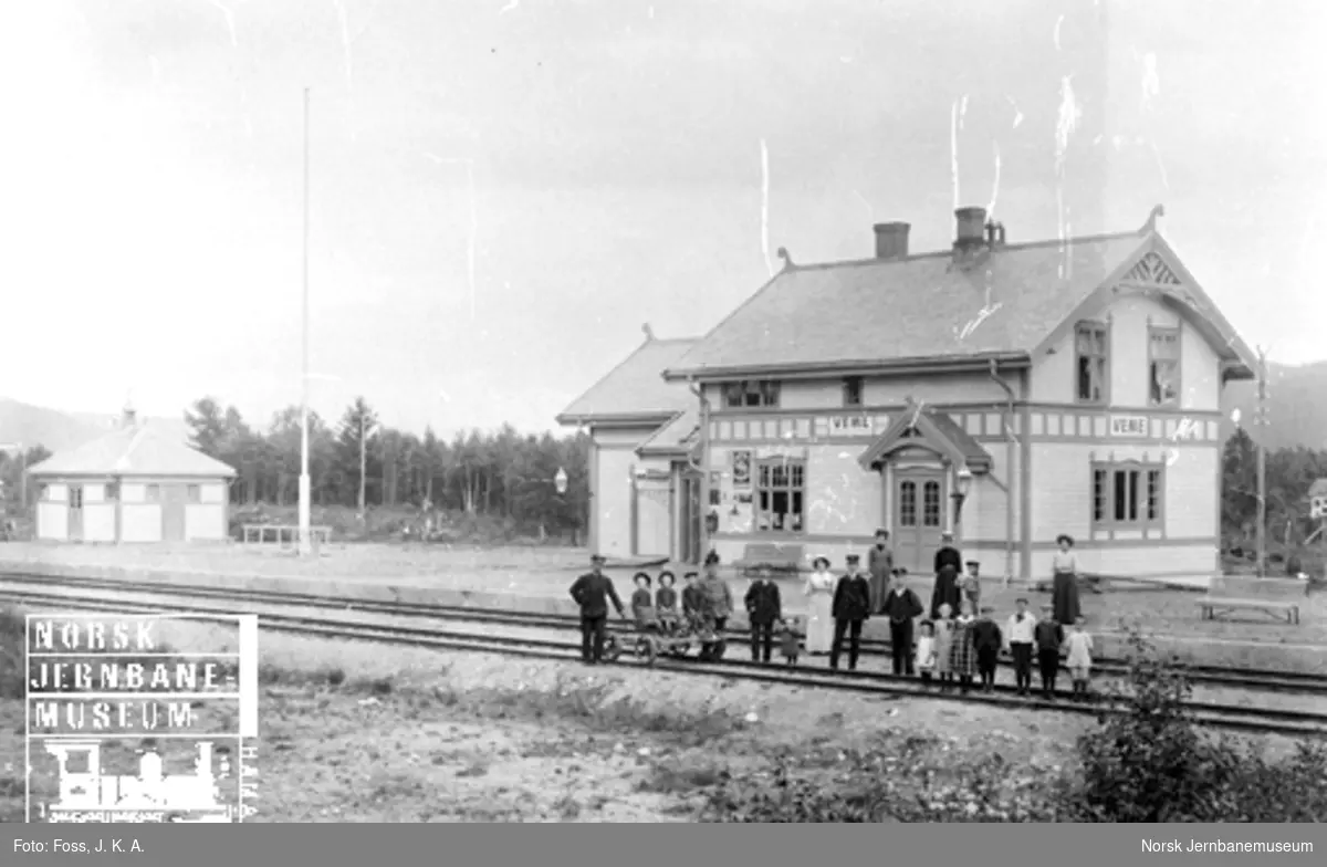 Veme stasjonsbygning med stasjonsbetjeningen og andre oppstilt for fotografering i sporene
