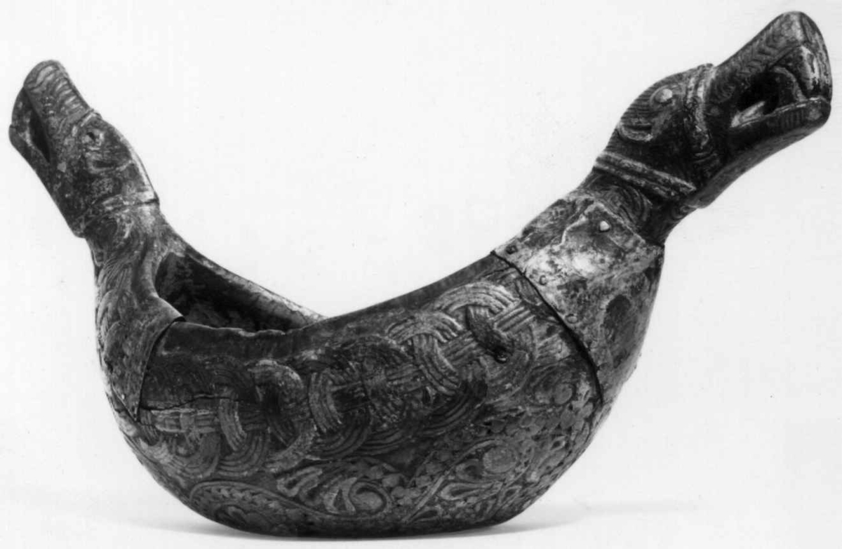 Bolle med håndtak formet som dragehovden. Flatskurd dekor: Geoometrisk bånd. Polykrom maling i flere lag.