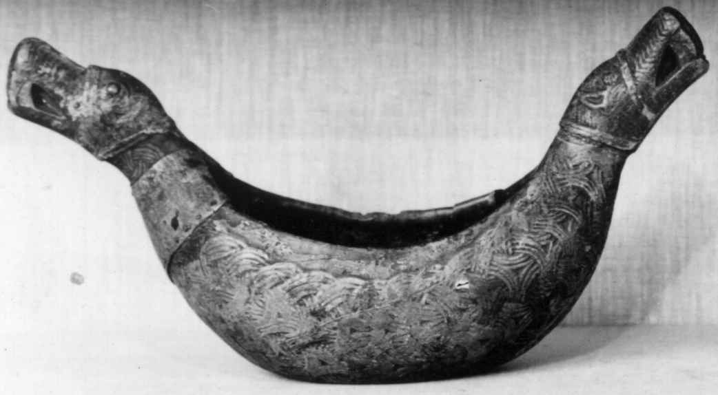 Bolle med håndtak formet som dragehovden. Flatskurd dekor: Geoometrisk bånd. Polykrom maling i flere lag.