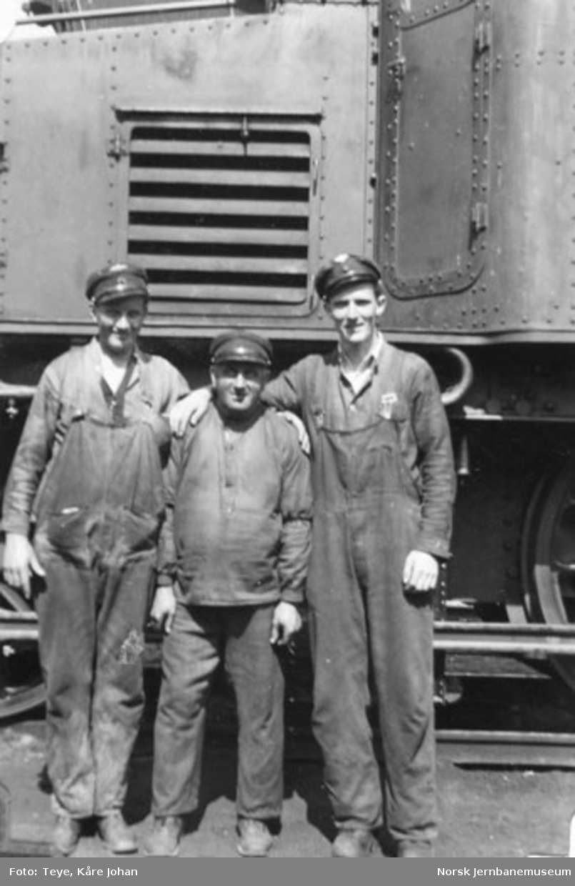 Tre mann oppstilt for fotografering ved et lokomotiv utenfor lokomotivstallen på Sundland