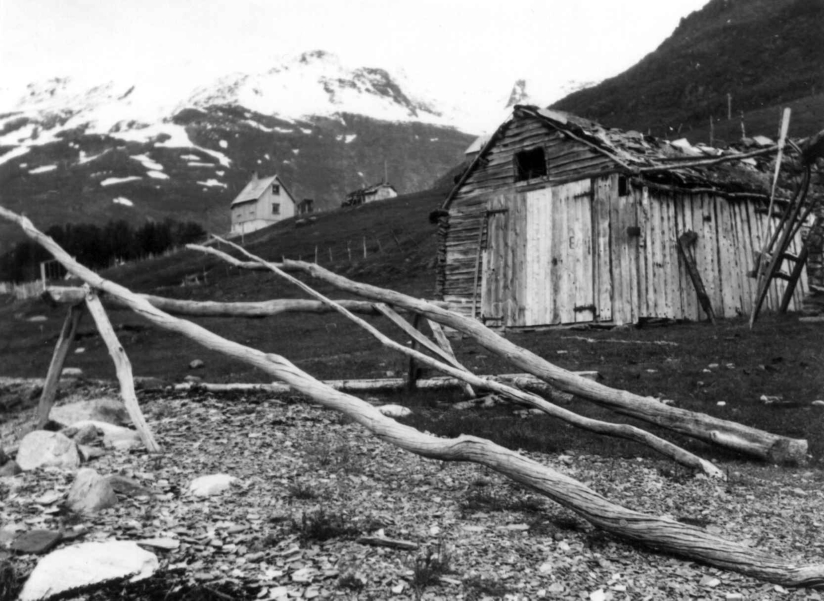 Garnhjell, stativ for oppheng av fiskegarn foran en sjøbu. I bakgrunnen en bolig og uthus. Birtavarre 1948.