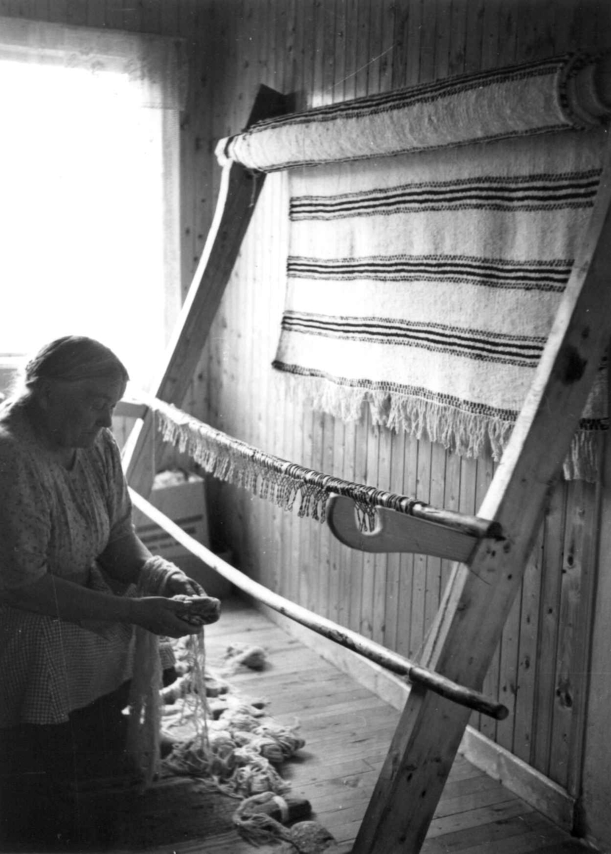 Greneveving (29). Anne Hansen er ferdig med greneteppet og holder på med demonteringen. Manndalen 1955.