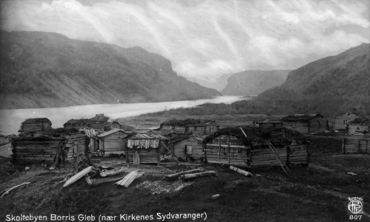 Oversiktsbilde med bebyggelse i skoltebyen Boris Gleb nær Kirkenes. Hus i tømmer. I bakgrunnen fjord og fjell.