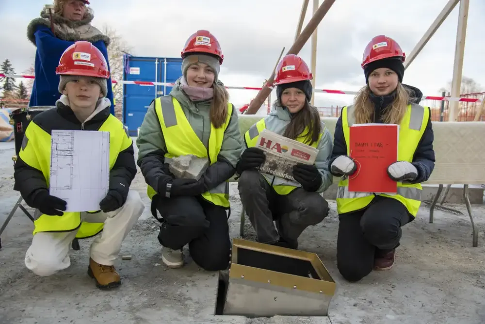 De fire skoleelevene som la ned grunnsteinen, viser det de la ned: Kaleb Sørlie, elev fra Solvang skole i Hamar kommune, la ned arkitekttegningene. Anbjørg Westad Skjelseth, elev Stavsberg skole i Ringsaker kommune, la ned gårsdagens eksemplar av Hamar Arbeiderblad da det ikke kommer ut papiravis på onsdager. Signe-Jarlene Larsen, elev fra Jønsrud skole i Løten kommune, la ned skriv fra hver av skoleklassene om tida vi lever i og dagen i dag, og Vilde Svartnes Andersen, elev ved Stange skole i Stange kommune, la ned en middelalderstein som knytter oss til den første byggeperioden på Domkirkeodden. 