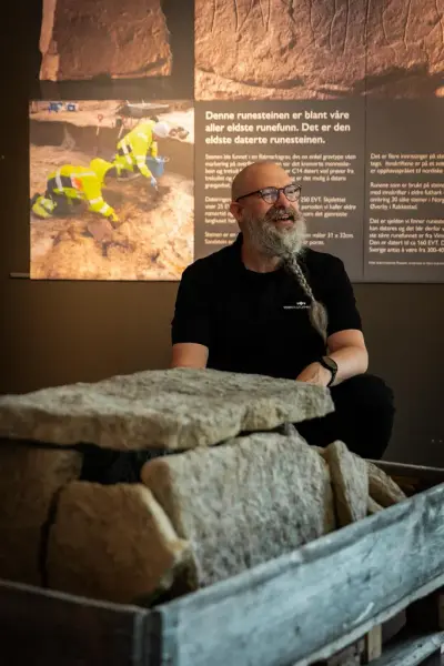 Arkeolog ved Veien kulturminnepark sitter ved store stener som er satt sammen. Dette er en grav funnet ved utgravningene ved Svingerud