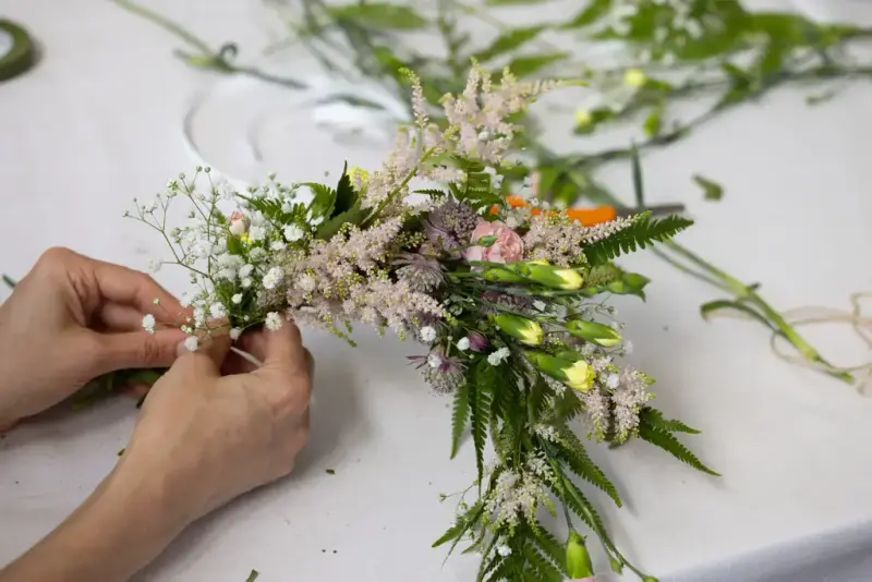 Hands making a flower crown with wildflowers during the Midsummer Festival at Norsk Folkemuseum.