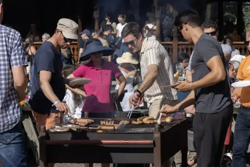 Festivaldeltakere griller pølser og burgere ved fellesgrill under Sankthansfestivalen på Norsk Folkemuseum.